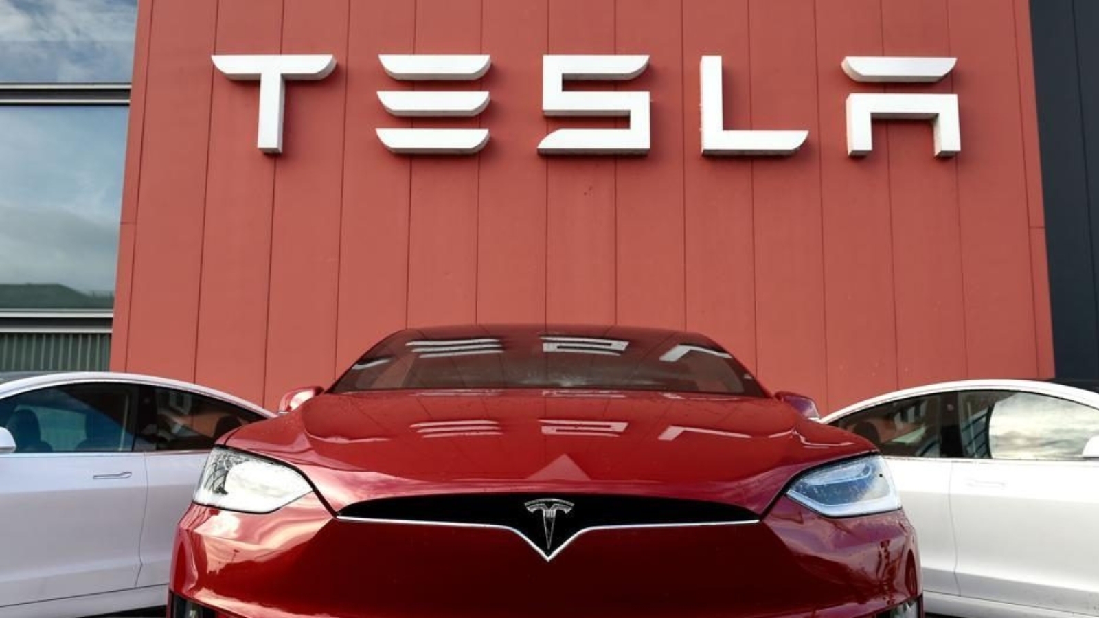 Tesla cars in front of the company logo